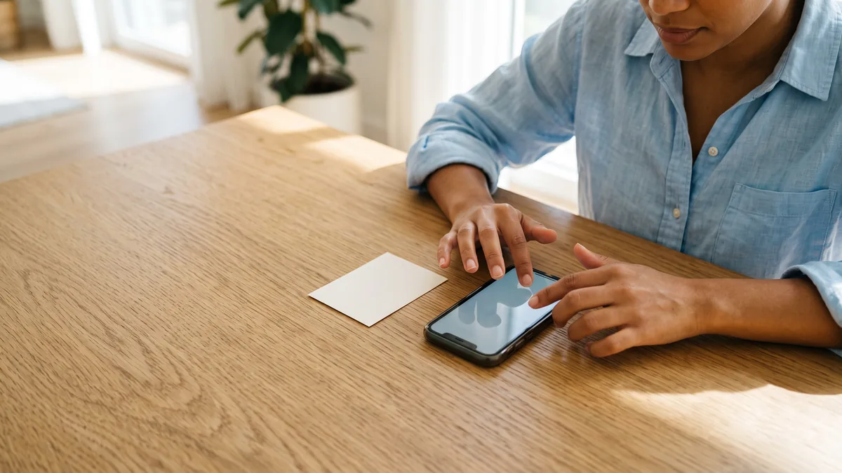 Una tarjeta sin marca y un teléfono sobre la mesa mientras alguien carga saldo